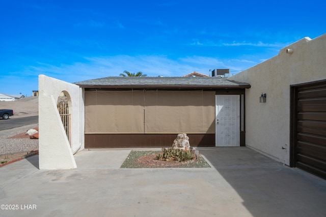 view of side of home featuring a shingled roof and stucco siding