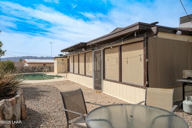 view of home's exterior featuring outdoor dining area, a patio area, and a fenced in pool