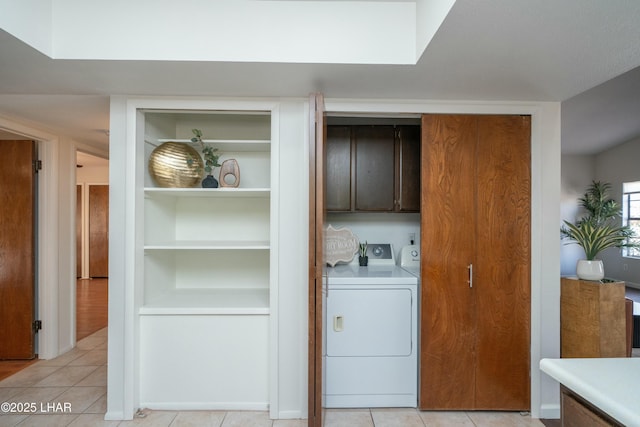 clothes washing area with separate washer and dryer, light tile patterned flooring, and cabinet space