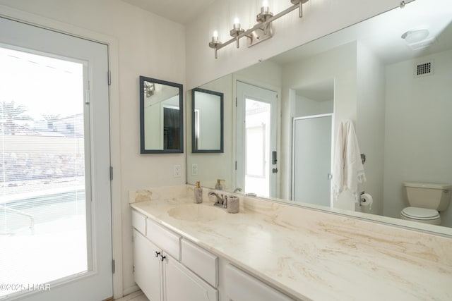 full bathroom with toilet, vanity, a shower stall, and visible vents