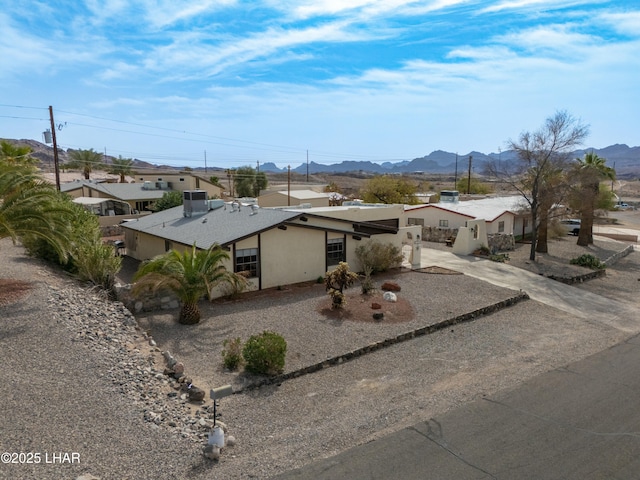 view of front facade featuring stucco siding, driveway, and a mountain view