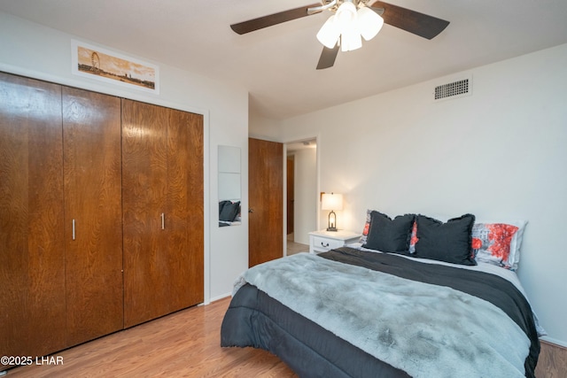 bedroom featuring ceiling fan, a closet, visible vents, and wood finished floors