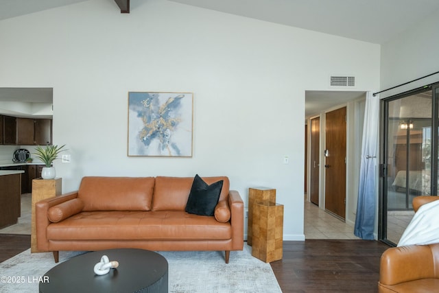 living area with high vaulted ceiling, baseboards, visible vents, and wood finished floors