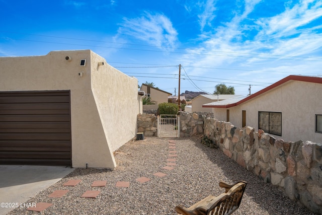 view of side of home with fence, a gate, and stucco siding