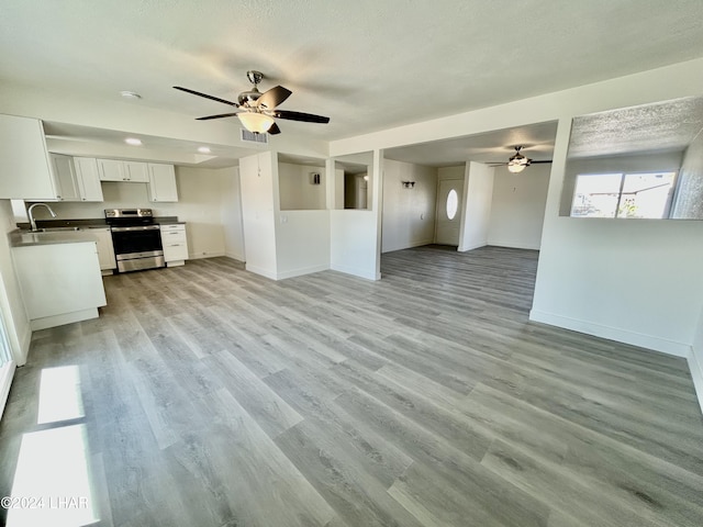 unfurnished living room featuring sink, a textured ceiling, ceiling fan, and light wood-type flooring