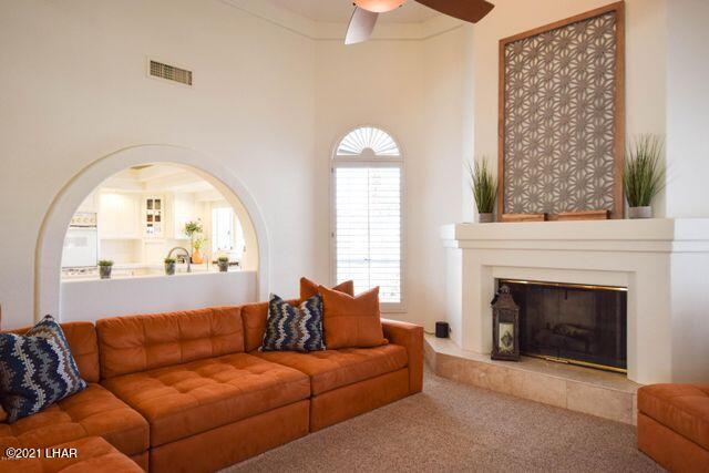 living room featuring carpet floors, ceiling fan, and a high ceiling