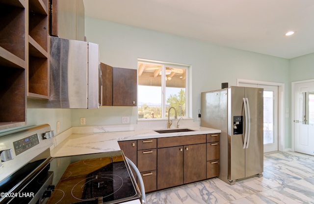 kitchen with light stone countertops, recessed lighting, appliances with stainless steel finishes, marble finish floor, and a sink