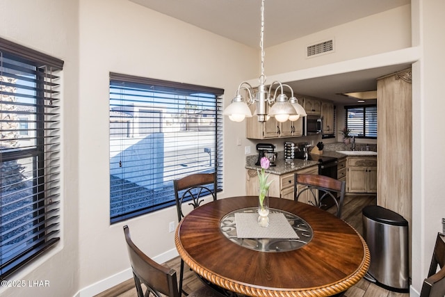 dining space with an inviting chandelier, sink, a wealth of natural light, and light hardwood / wood-style floors