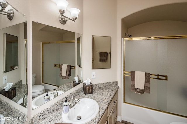 full bathroom featuring vanity, bath / shower combo with glass door, and toilet