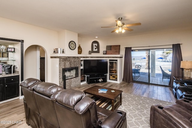 living room with wood-type flooring, a fireplace, and ceiling fan