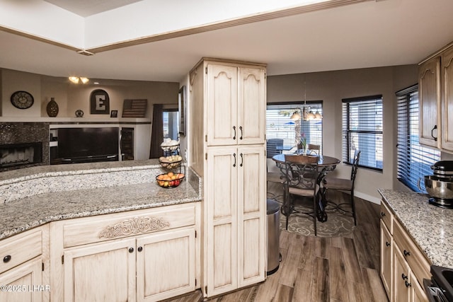 kitchen featuring dark hardwood / wood-style floors, a fireplace, stove, light stone counters, and light brown cabinets