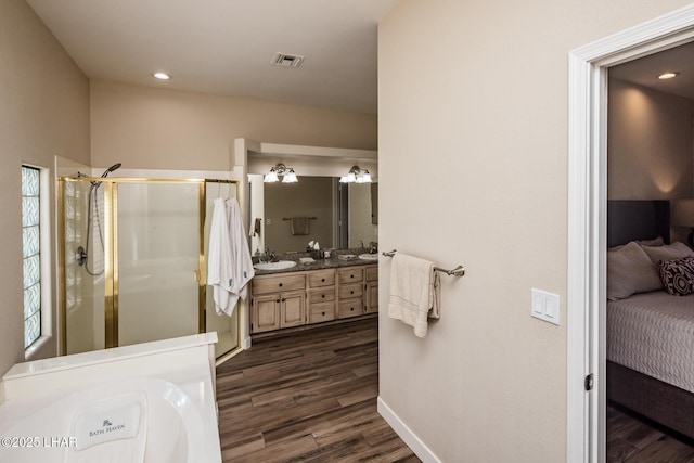 bathroom featuring hardwood / wood-style flooring, plus walk in shower, and vanity