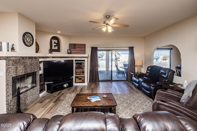 living room featuring ceiling fan, wood-type flooring, and a tiled fireplace