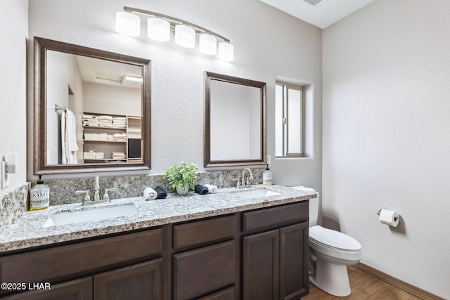 full bath with double vanity, toilet, wood finished floors, and a sink