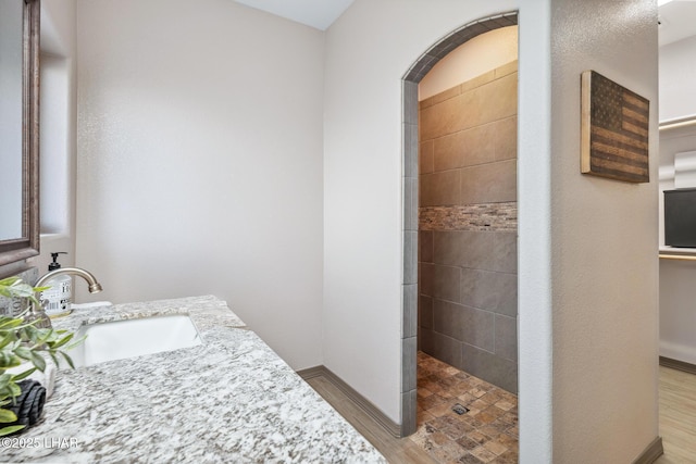 bathroom featuring baseboards, vanity, and walk in shower