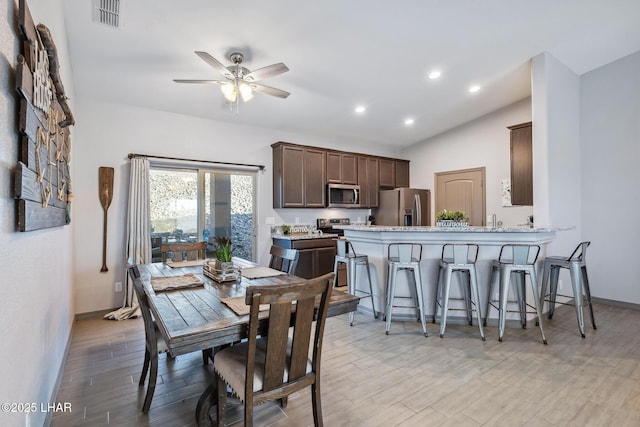 dining space featuring baseboards, visible vents, lofted ceiling, ceiling fan, and light wood-style floors