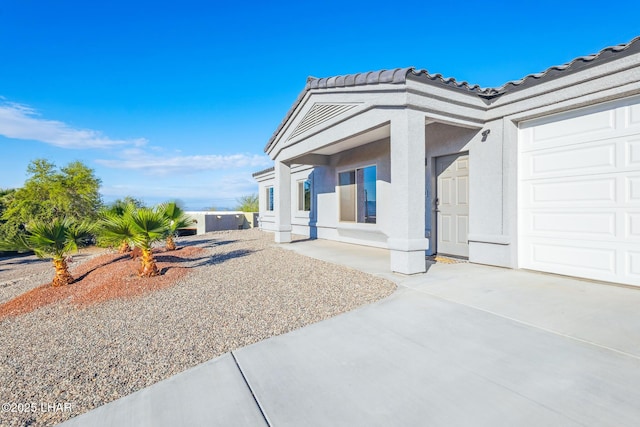 exterior space with a tile roof, an attached garage, and stucco siding