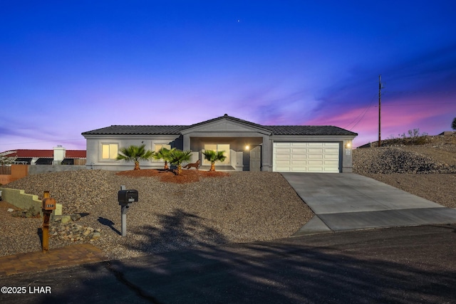 view of front of home featuring a tiled roof, stucco siding, driveway, and a garage