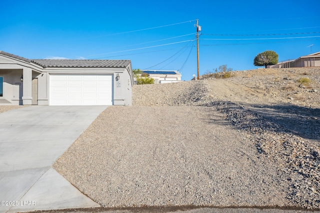 view of yard featuring concrete driveway and a garage