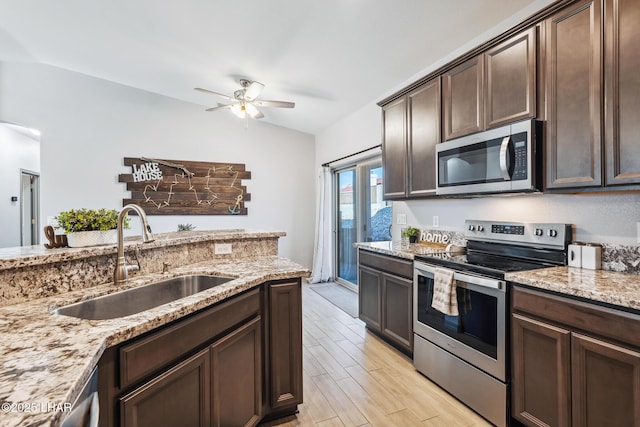 kitchen featuring dark brown cabinets, lofted ceiling, appliances with stainless steel finishes, light wood-style floors, and a sink