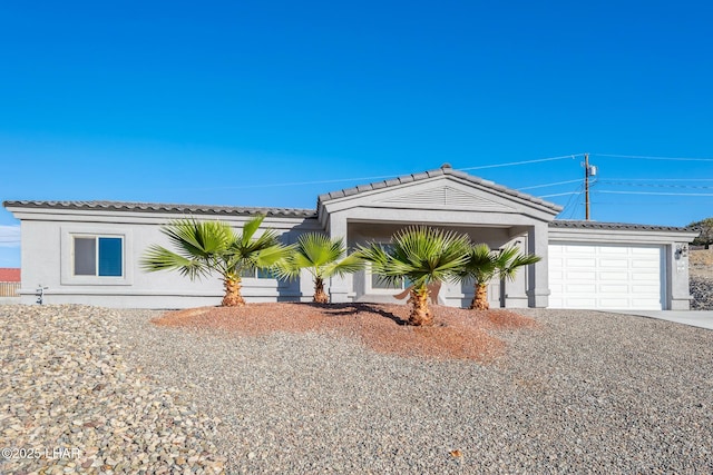 view of front facade with stucco siding, a garage, driveway, and a tiled roof