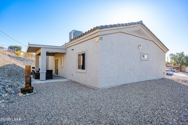 rear view of property featuring stucco siding, a patio, central AC unit, and a tile roof