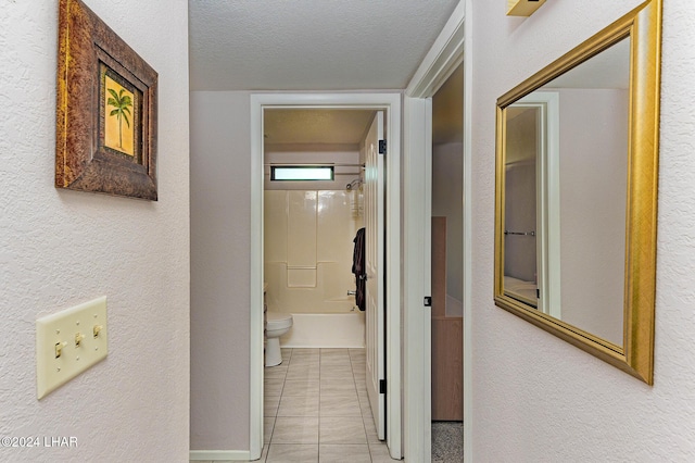 hall featuring a textured ceiling and light tile patterned floors