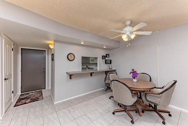 tiled dining area featuring ceiling fan and a textured ceiling