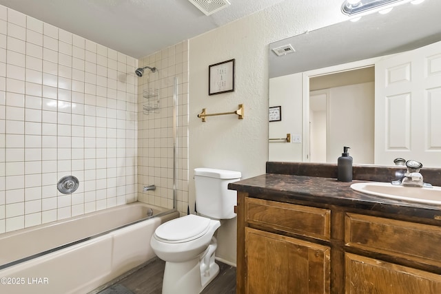 full bathroom with tiled shower / bath, vanity, toilet, and hardwood / wood-style floors