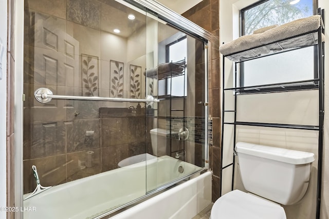 bathroom featuring toilet, combined bath / shower with glass door, and tile walls