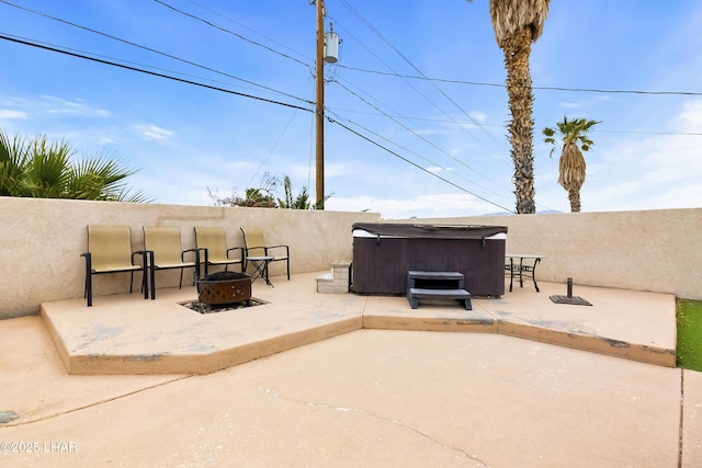 view of patio with a hot tub and an outdoor fire pit