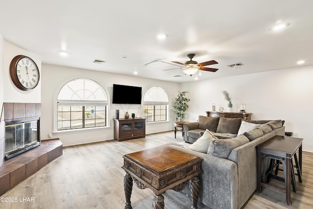 living room with ceiling fan, a fireplace, and light hardwood / wood-style floors