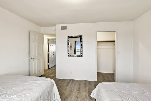 bedroom with a walk in closet, dark hardwood / wood-style floors, and a closet