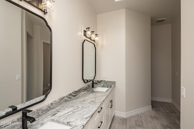 1650 E Sandra Dr, Lake Havasu City, AZ 86404 - bathroom featuring wood finished floors, double vanity, baseboards, and a chandelier