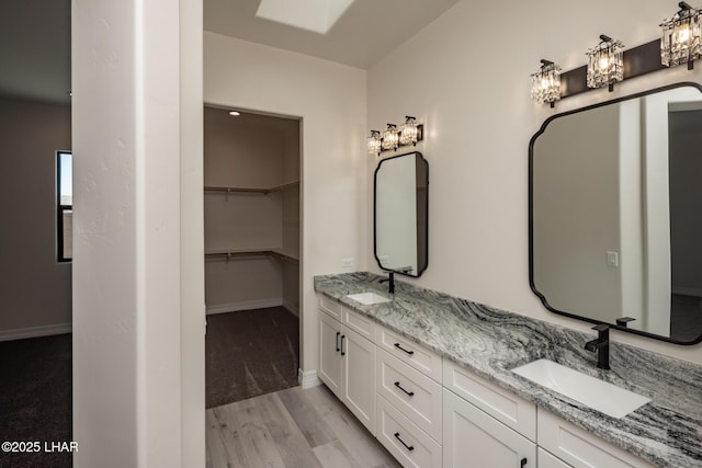 1650 E Sandra Dr, Lake Havasu City, AZ 86404 - bathroom featuring double vanity, wood finished floors, baseboards, and a spacious closet