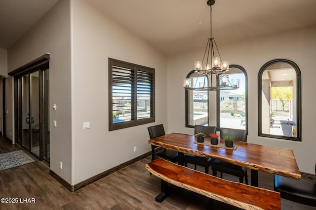 dining space with baseboards, wood finished floors, arched walkways, and a chandelier