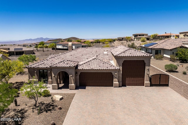 view of front facade featuring a gate, driveway, a tiled roof, a garage, and stucco siding
