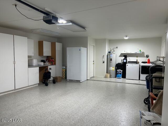 garage featuring a garage door opener, washer and clothes dryer, water heater, and white refrigerator