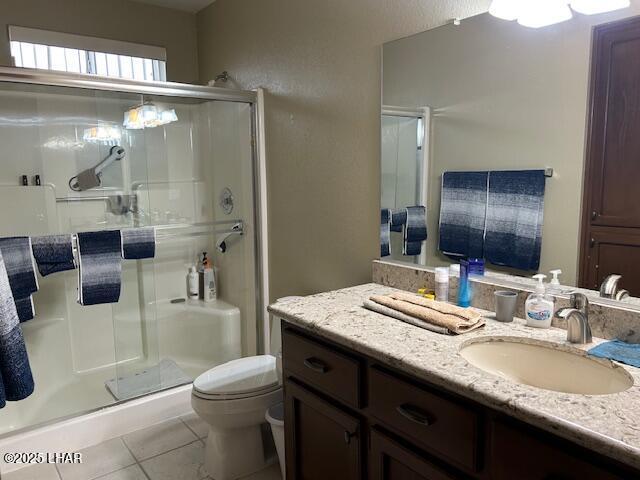 bathroom featuring tile patterned floors, toilet, an enclosed shower, and vanity