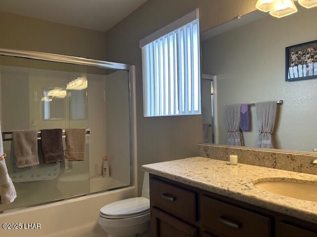 full bathroom with enclosed tub / shower combo, vanity, and toilet