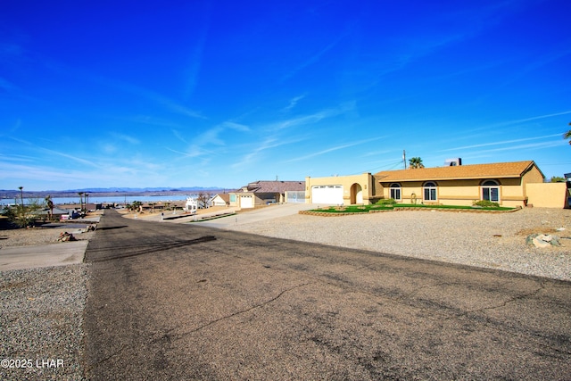 view of front of home with a water view, driveway, an attached garage, and stucco siding