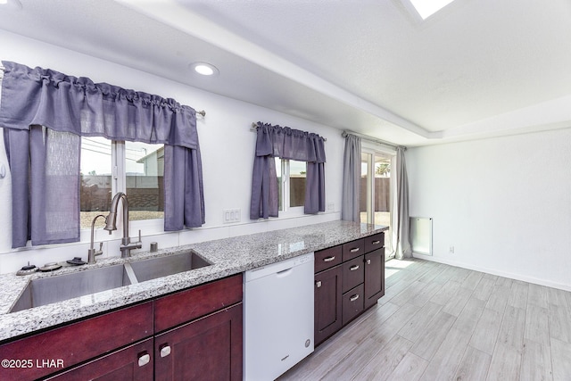 1880 Biscayne Ln, Lake Havasu City, AZ 86403 - kitchen with reddish brown cabinets, a sink, light wood-style floors, light stone counters, and white dishwasher