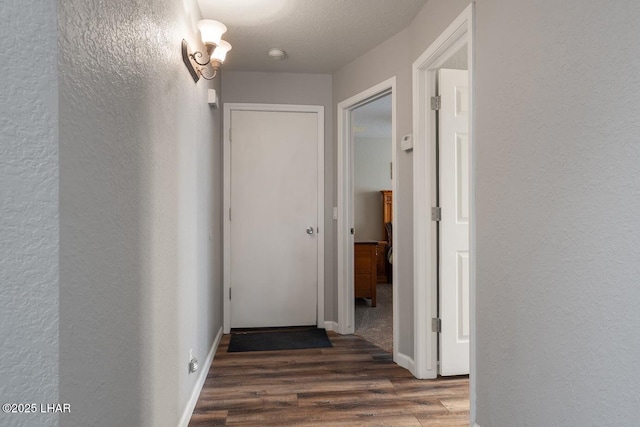 corridor featuring dark wood-type flooring and a textured ceiling