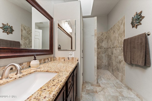 bathroom with vanity and a tile shower