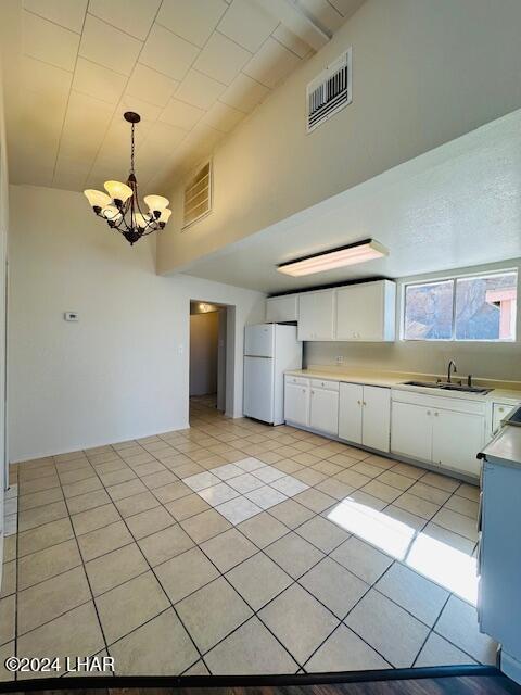 kitchen featuring sink, white cabinetry, hanging light fixtures, light tile patterned floors, and white refrigerator