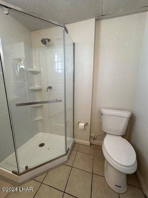 bathroom with tile patterned flooring, a shower with shower door, and toilet