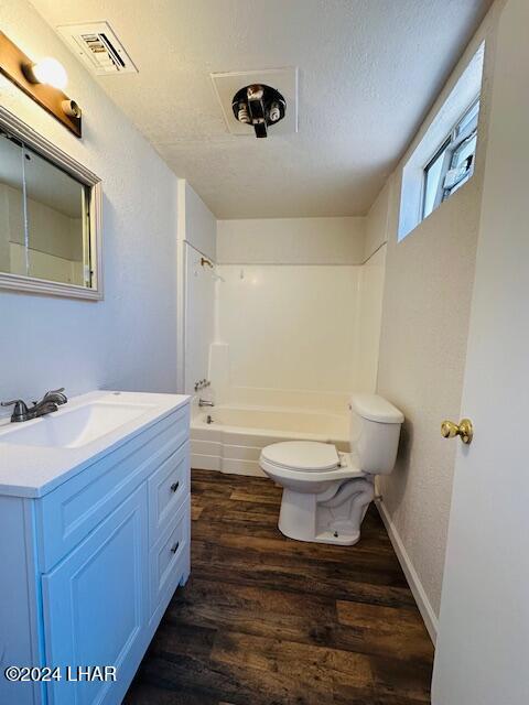 full bathroom featuring shower / bath combination, hardwood / wood-style floors, vanity, a textured ceiling, and toilet