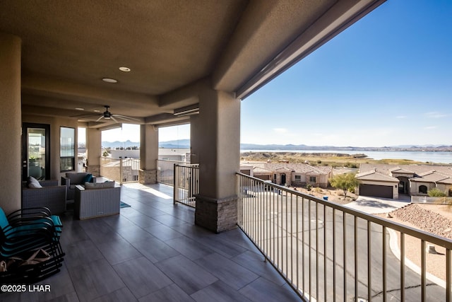 balcony with a water view, a residential view, an outdoor hangout area, and a ceiling fan