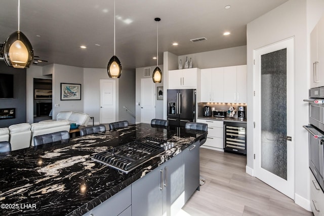 kitchen with white cabinets, wine cooler, open floor plan, pendant lighting, and high end fridge