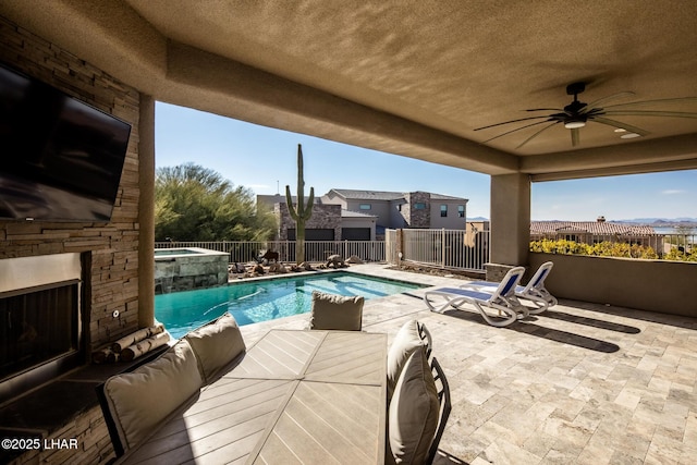 view of swimming pool with a patio, an outdoor stone fireplace, fence, and a pool with connected hot tub